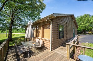 A log cabin with a deck, outdoor seating, and a view of the surrounding greenery. - Fishtale Lodge (Buchanan)