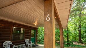 A wooden cabin with a porch, a green door, and two white chairs. - Fishtale Lodge (Buchanan)