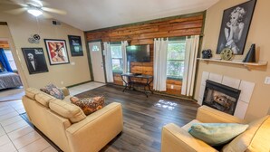 A living room with a beige sofa, a television, a fireplace, and wooden walls. - Fishtale Lodge (Buchanan)