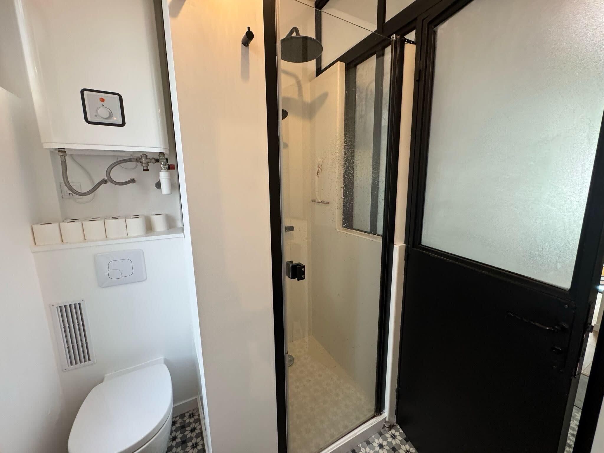 A bathroom with a toilet, a shower with a glass door, and a sink with a faucet.