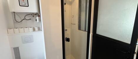 A bathroom with a toilet, a shower with a glass door, and a sink with a faucet.