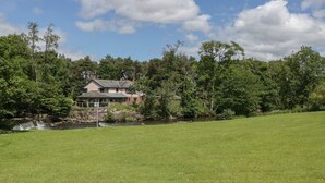 Ein Haus mit Teich, umgeben von Bäumen und einer Wiese.