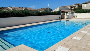 Una piscina rectangular con agua azul cristalina, rodeada por un bordeado de baldosas.