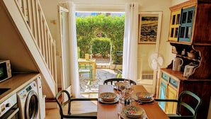 Una cocina con una mesa de comedor dispuesta para cuatro, una lavadora y una escalera que lleva a un área exterior con vegetación.