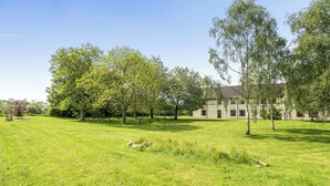 Un champ herbeux avec des arbres et un bâtiment en arrière-plan.