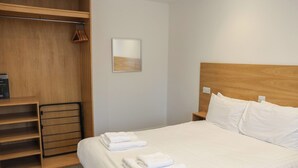 A neatly arranged hotel room with a large bed, a wooden wardrobe, and a small bedside table. - Jubilee Two Bedroom Bungalow Pet Free (Penrith)