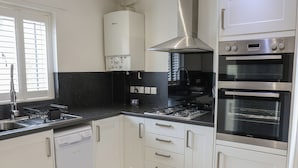 A modern kitchen with white cabinets, a stainless steel range, a dishwasher, and a built-in oven. - Jubilee Two Bedroom Bungalow Pet Free (Penrith)