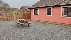 A red building with two windows and a wooden fence in the background. - Jubilee Two Bedroom Bungalow Pet Free (Penrith)