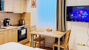 A compact room with a kitchenette, a dining area, and a TV. - Riverside Apartment 12 (Hlavní město Praha)