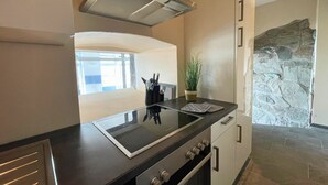 A modern kitchen with a black countertop, stainless steel appliances, and a stone accent wall. - FeWo im Hang direkt am Hafen, 6 Betten, 175m2 (Sassnitz)