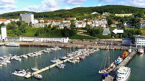 A marina with numerous boats docked, surrounded by residential buildings and a hilly landscape in the background. - FeWo im Hang direkt am Hafen, 6 Betten, 175m2 (Sassnitz)