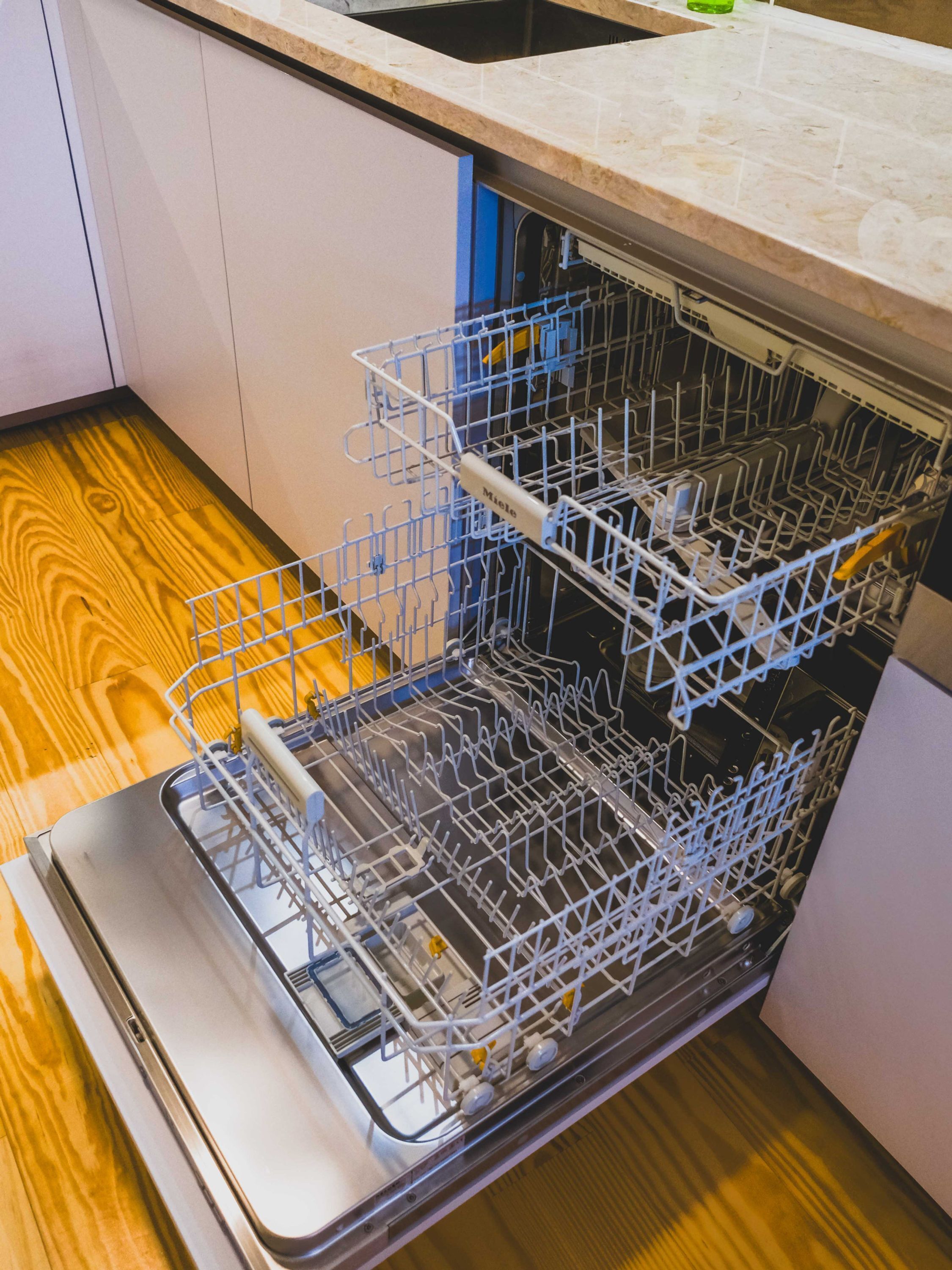 Un lavavajillas abierto con suelo de madera y encimera de cocina.