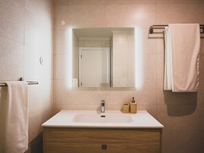 A bathroom with a white sink, a mirror, and a towel rack. - Casa P ra Muralha in Bidos (Obidos)
