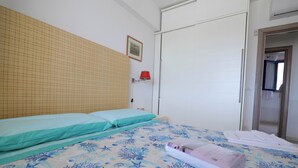 A bedroom with a bed, a wall-mounted lamp, a wardrobe, and a door leading to another room. - Relax in Leuca - Terrace with Panoramic Sea View - Casa Michele (Santa Maria di Leuca)