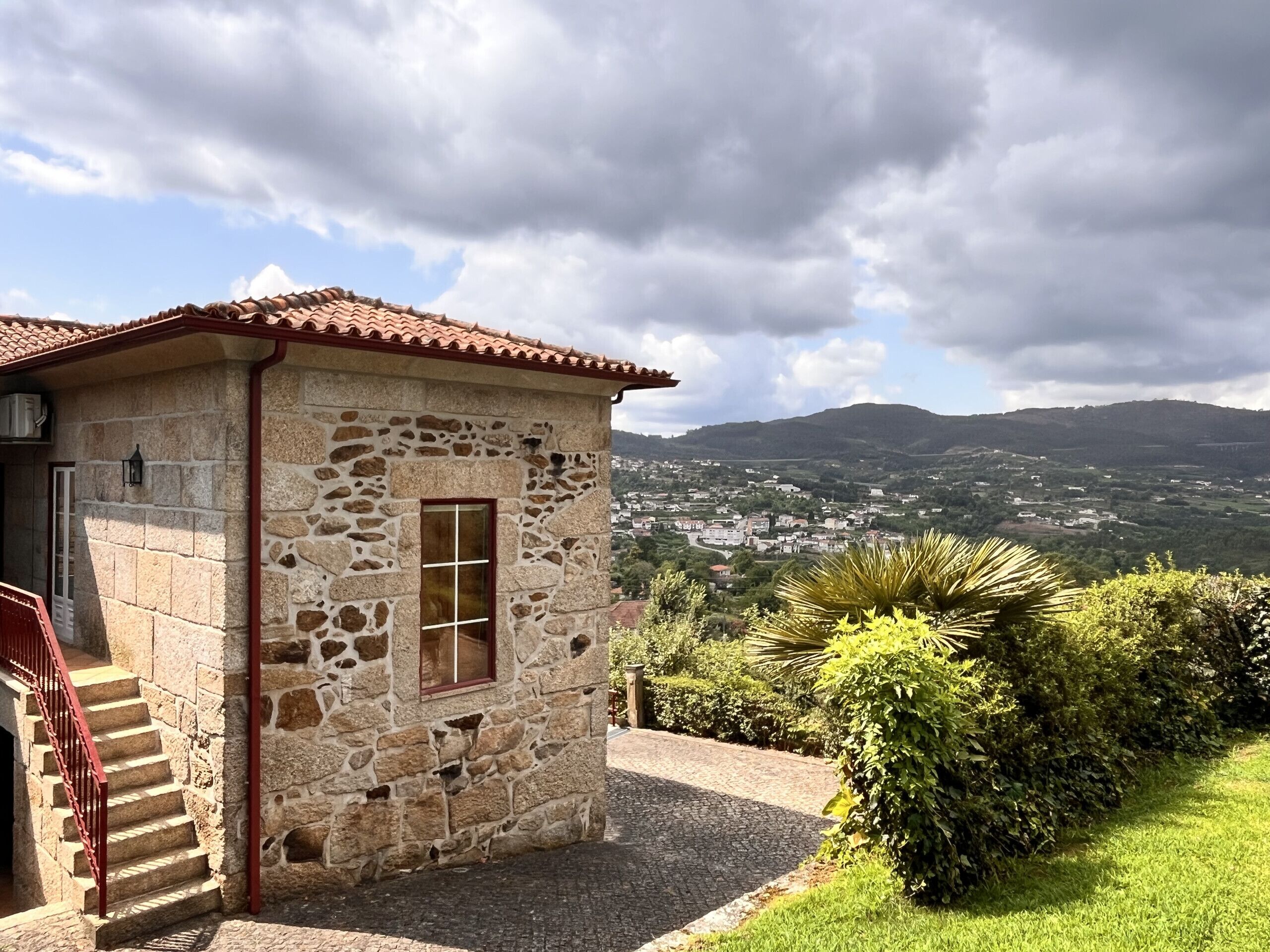 Un edificio in pietra con tetto in tegole rosse, una finestra e una scala che conduce a un piano superiore.