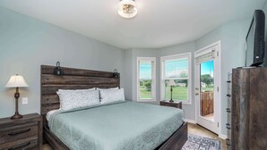 A bedroom with a large bed, a nightstand, a dresser, and a television. - Family Fun Retreat, Games & Fire Pit, Near Eureka (Holiday Island)
