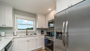 A modern kitchen with white cabinets, stainless steel appliances, and a window overlooking a scenic view. - Family Fun Retreat, Games & Fire Pit, Near Eureka (Holiday Island)