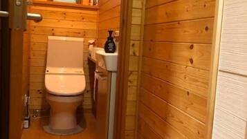 A wooden-paneled bathroom with a toilet, sink, and window.