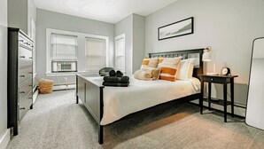 A bedroom with a bed, bedside table, lamp, and a picture on the wall. - A brick's throw away to Sally's Apizza! (New Haven)