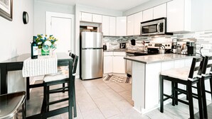 A modern kitchen with white cabinets, stainless steel appliances, and a central island. - A brick's throw away to Sally's Apizza! (New Haven)