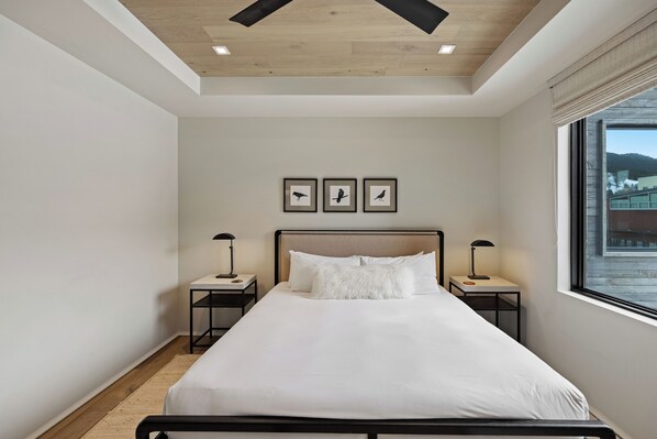 Un dormitorio ordenado con una cama grande, dos mesitas de noche y cuadros decorativos en la pared.