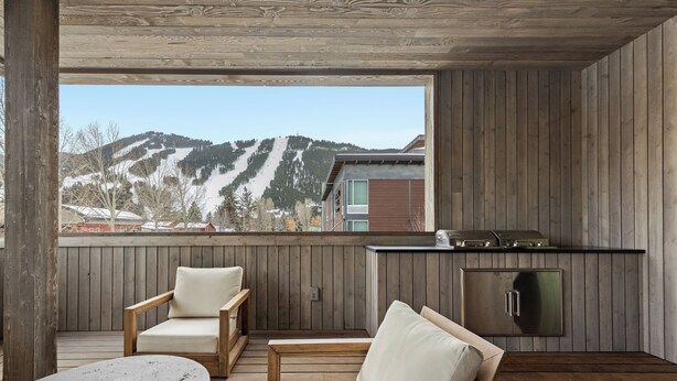 A wooden deck with a view of a mountain, a kitchen area, and seating.