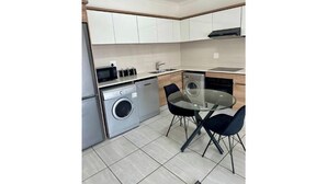 Una cocina compacta equipada con lavadora, lavavajillas, pileta y una mesa de comedor con sillas.