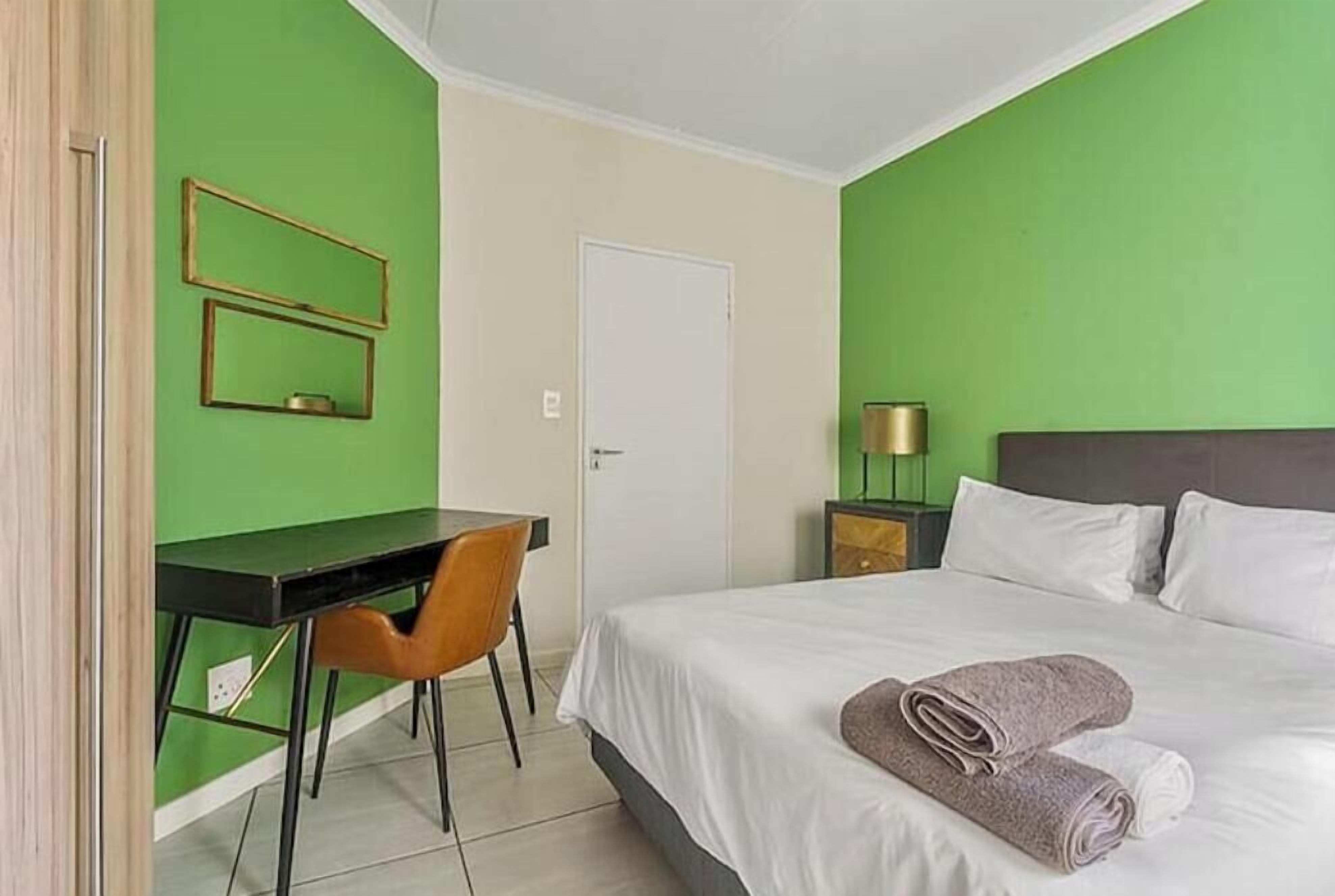 Hotellihuone, jossa on sänky, työpöytä ja tuoli.