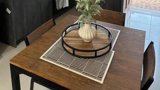 Una cocina moderna con armarios oscuros, una isla central y una mesa de comedor con un jarrón de flores.