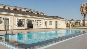 A swimming pool adjacent to a building with multiple doors and windows, suggesting a hotel or resort setting. - Gem in Fourways Modern 2-Bed Apartment (Randburg)