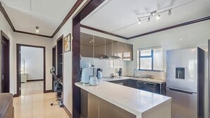 A modern kitchen with a central island, stainless steel appliances, and a large window providing natural light. - Gem in Fourways Modern 2-Bed Apartment (Randburg)