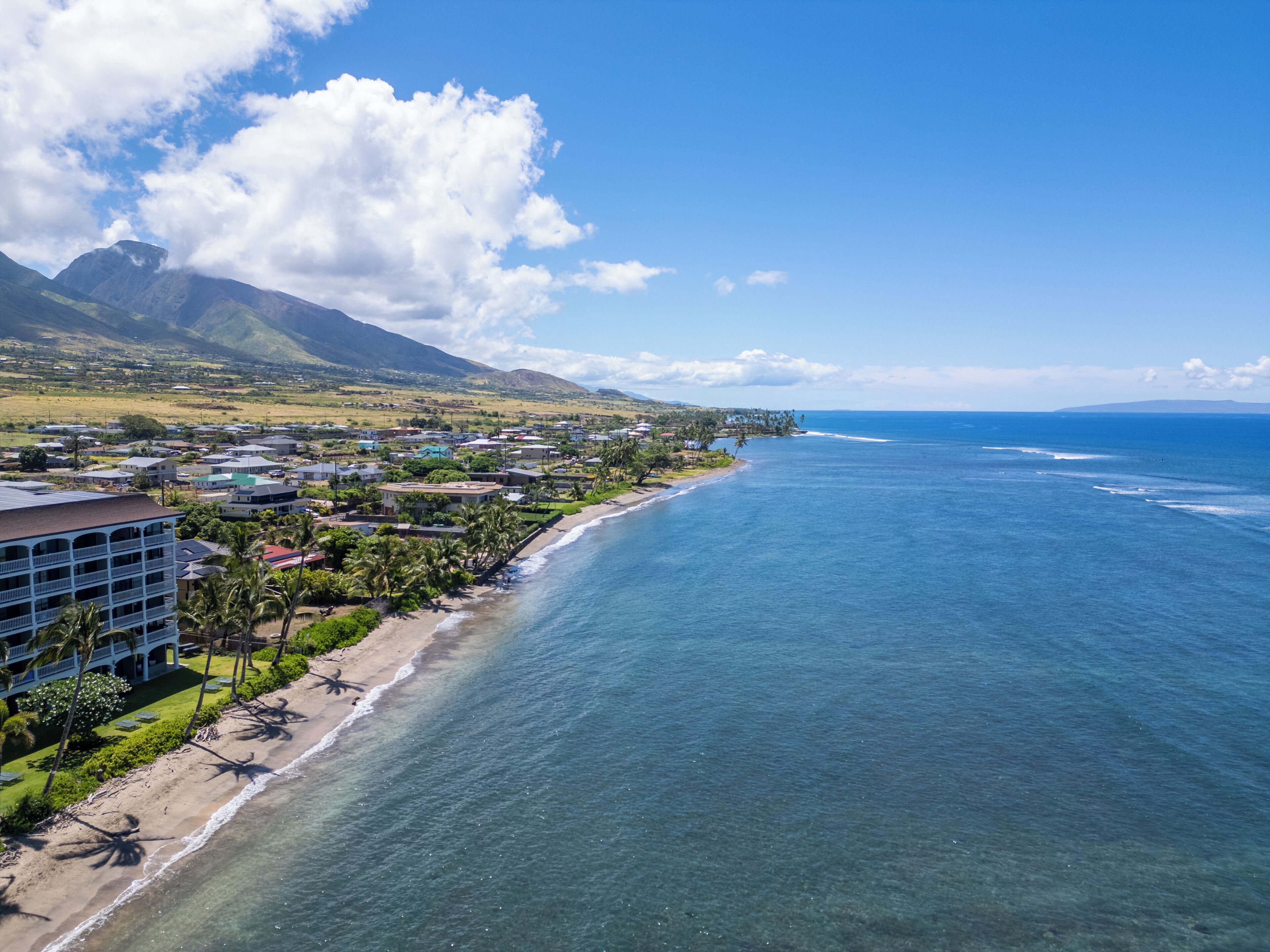 A coastal town with a beach, ocean, and mountains in the background.