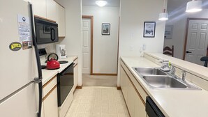 A compact kitchen with a microwave, kettle, and sink.