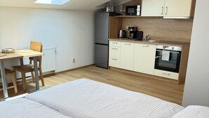 A modern bedroom with a large bed, a skylight, a kitchenette, and a dining area. - Riverside Apartment 15 (Hlavní město Praha)