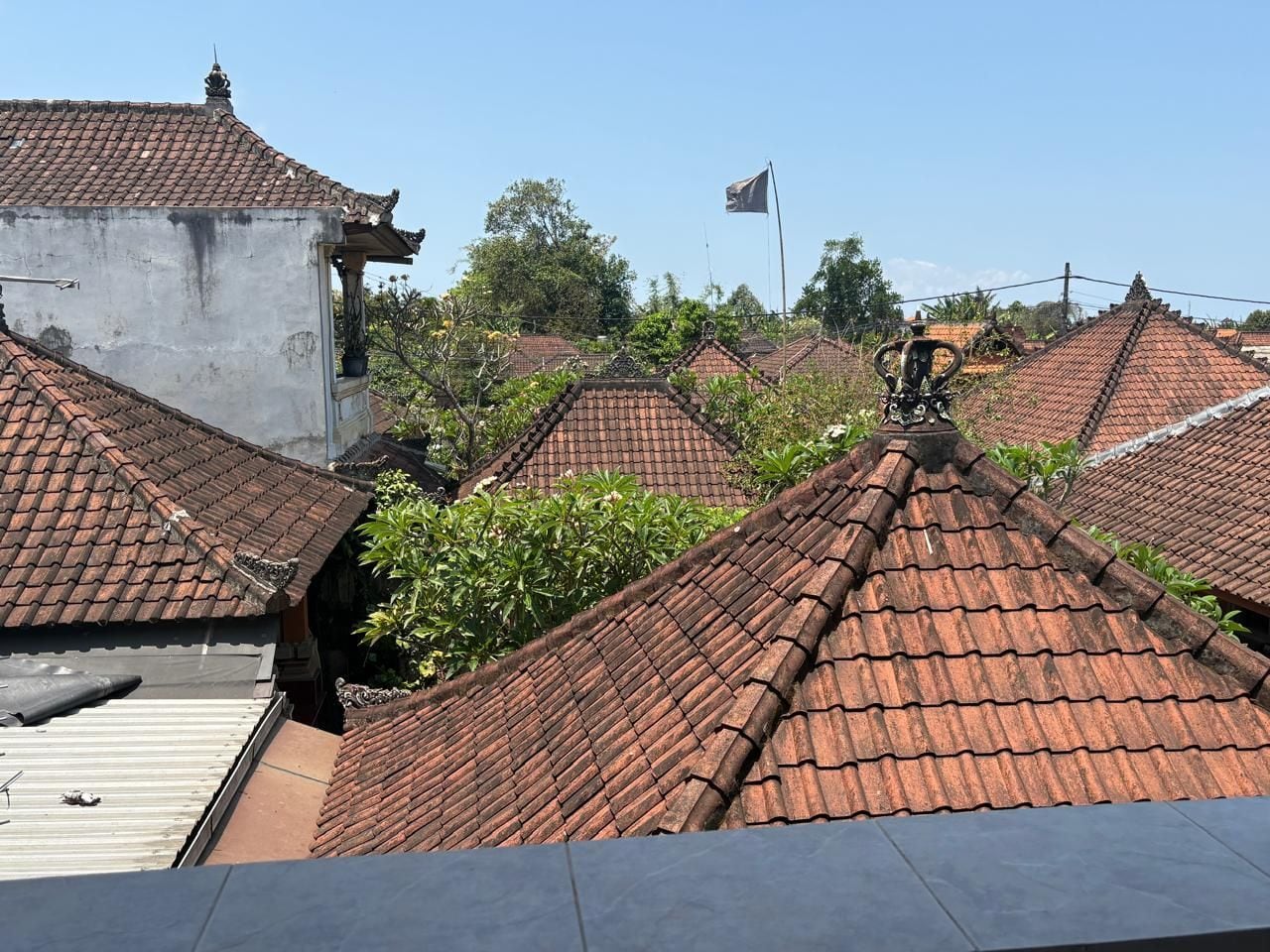 A residential area with multiple houses featuring red-tiled roofs and a flagpole with a flag.