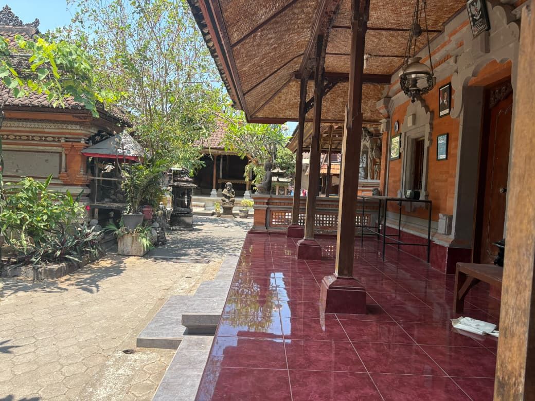 An outdoor covered area with tiled flooring, potted plants, and traditional architectural elements.