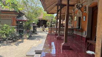 An outdoor covered area with tiled flooring, potted plants, and traditional architectural elements.