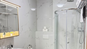 A modern bathroom with a glass-enclosed shower, a sink with a mirror, a toilet, and a washing machine. - Riverside Apartment 16 (Hlavní město Praha)
