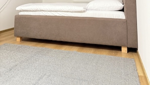 A modern bedroom with a bed, a grey rug, and a TV mounted on the wall. - Riverside Apartment 16 (Hlavní město Praha)