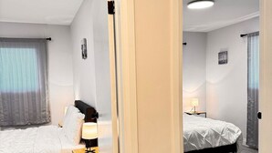 A hotel room with two beds, a desk, and a mirror.