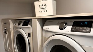 A laundry area with two front-loading washing machines and a white shelf above them.
