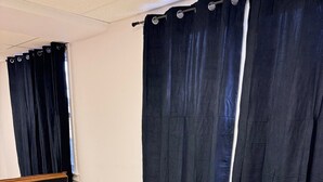 A conference room with a white table, six chairs, a potted plant, and dark curtains.