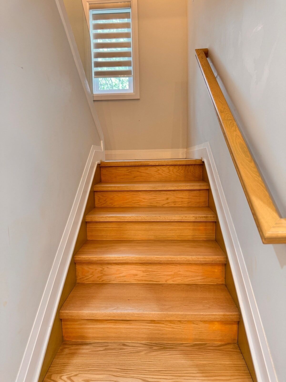 A wooden staircase with white trim and a handrail.