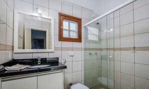 A bathroom with a glass shower enclosure, a sink with a mirror, and a toilet. - Encantador Apto Beira-mar Floripa Rpb037 (Florianópolis)