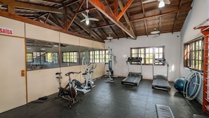 A gym with exercise equipment, a mirrored wall, and a ceiling fan. - Encantador Apto Beira-mar Floripa Rpb037 (Florianópolis)