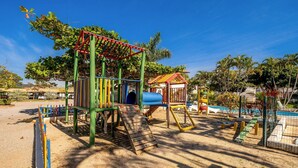 A playground with a slide, climbing structures, and a small shelter. - Encantador Apto Beira-mar Floripa Rpb037 (Florianópolis)