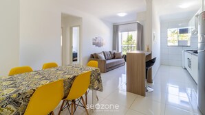 A modern living room with a sofa and a dining table with yellow chairs.
