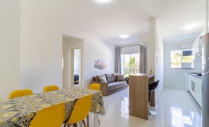 Een moderne woonkamer met een bank en een eettafel met gele stoelen.