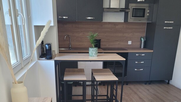 A modern kitchen with dark cabinets, a microwave, and a sink. There are two stools at the kitchen island.