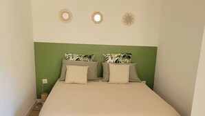 A bedroom with a bed, green headboard, and decorative wall mirrors.